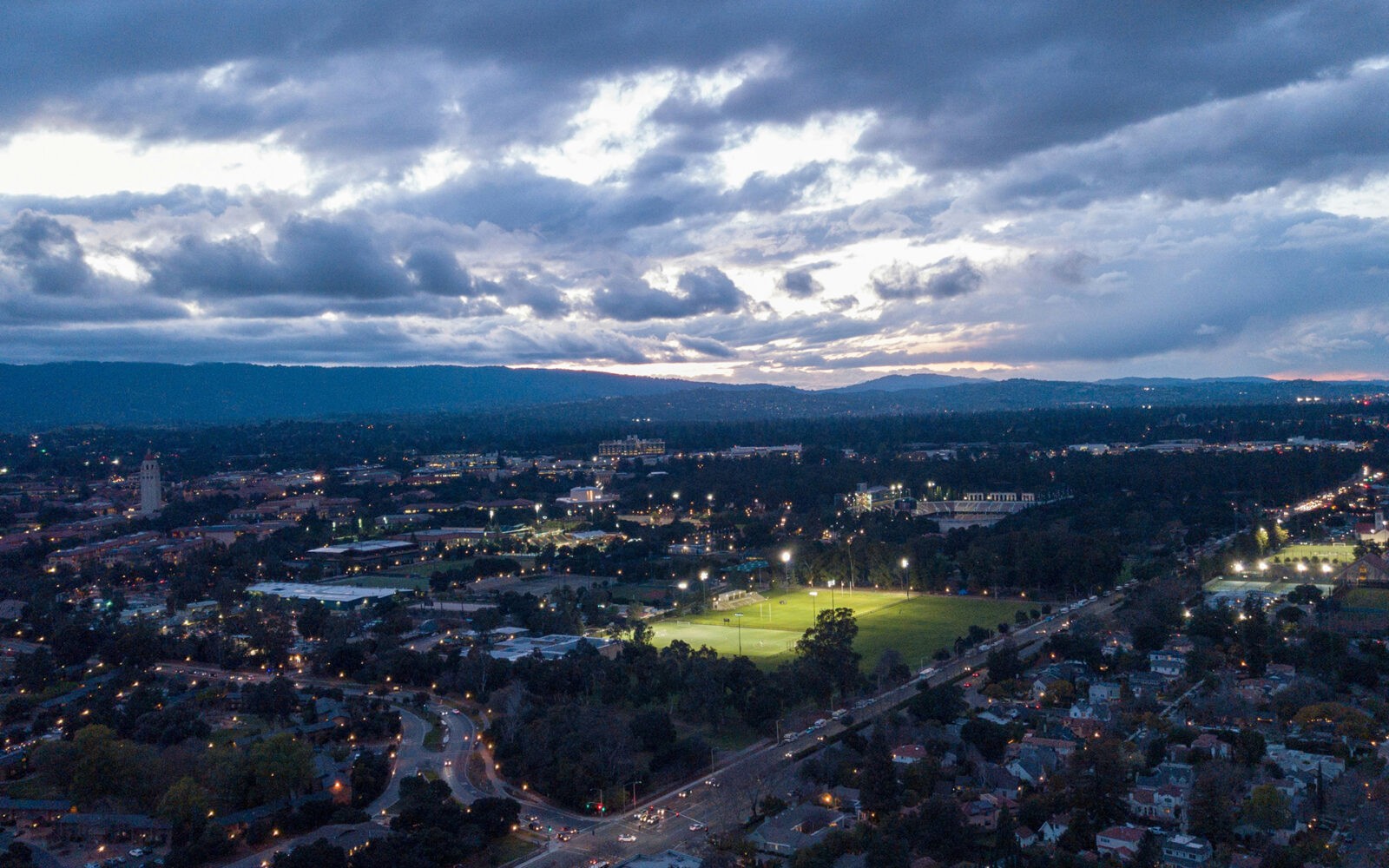 CloudMasonry - California Based Salesforce Consulting - Palo Alto Office Landing Page Image - Cityscape at dusk with illuminated sports fields.