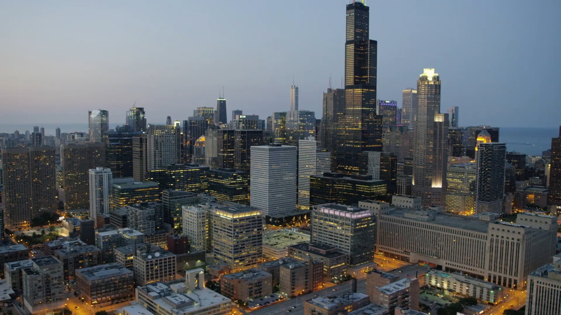 Chicago skyline at dusk with illuminated buildings.